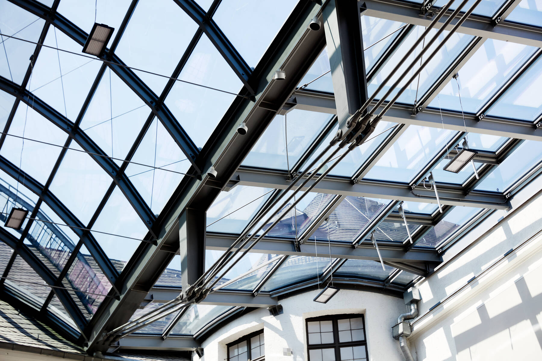 Weitwinkelaufnahme des lichtdurchfluteten Innenhofs im Historischen Museum Speyer unter der filigranen ISOLAR Glasdachkonstruktion.